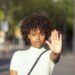 Young woman making a stop or stop gesture with the raised palm of her hand as she blocks access